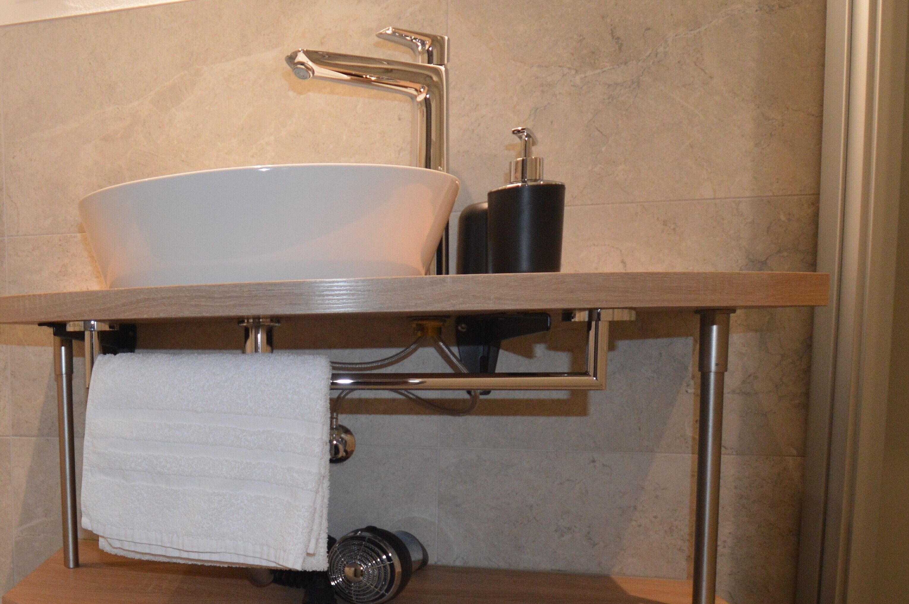 A bathroom with a white sink, a towel rack, and a soap dispenser.
