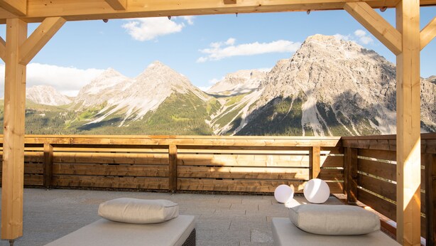 A wooden deck with two lounge chairs and a view of mountains. - Hotel Hohe Promenade Arosa (Arosa)
