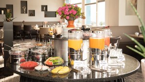 A buffet with various food items and beverages, including orange juice and grapefruit juice. - Hotel Hohe Promenade Arosa (Arosa)