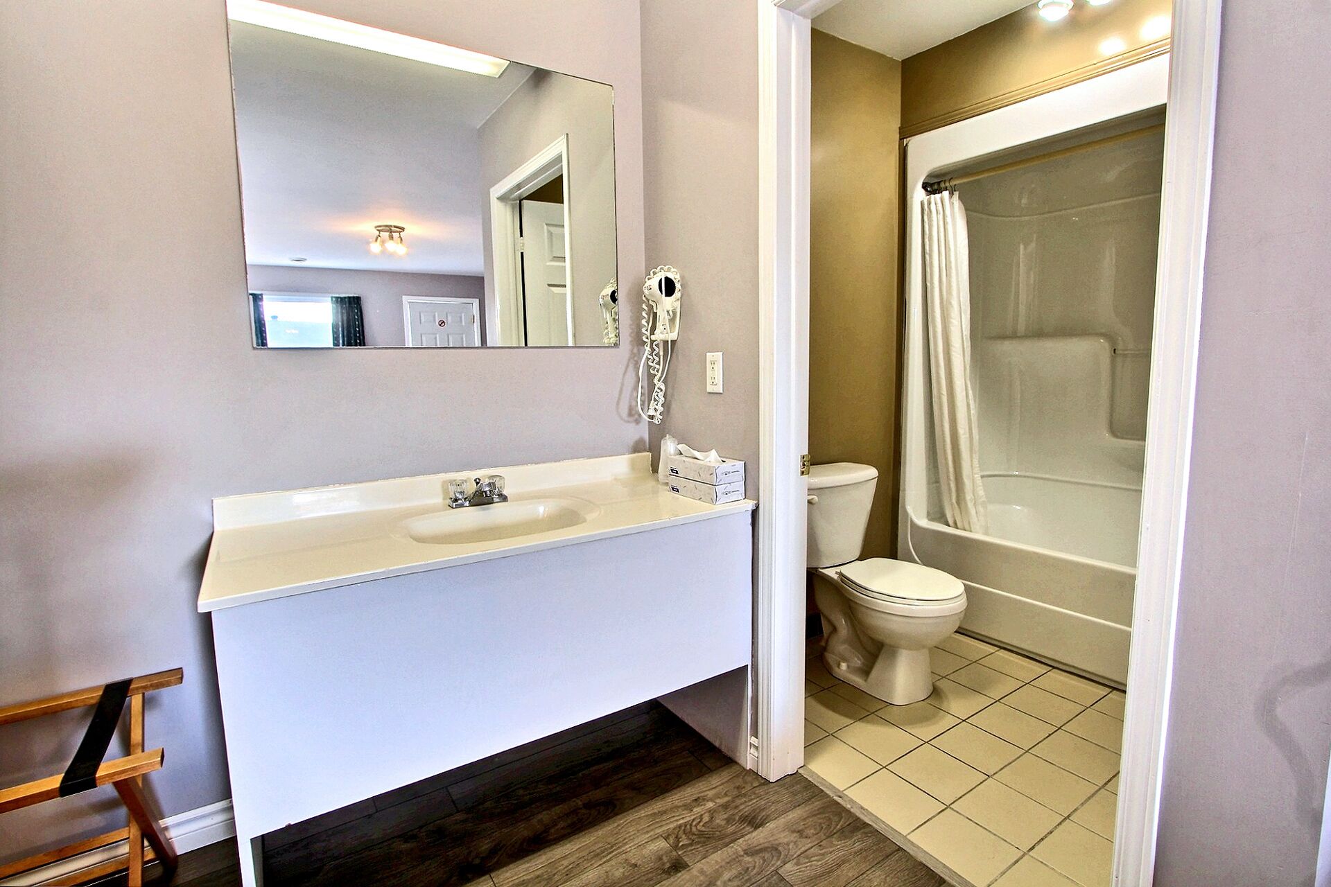 A bathroom with a white sink, mirror, toilet, and bathtub.