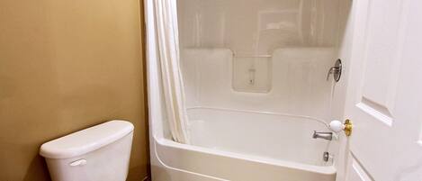 Un baño con inodoro, bañera y cortina de ducha.