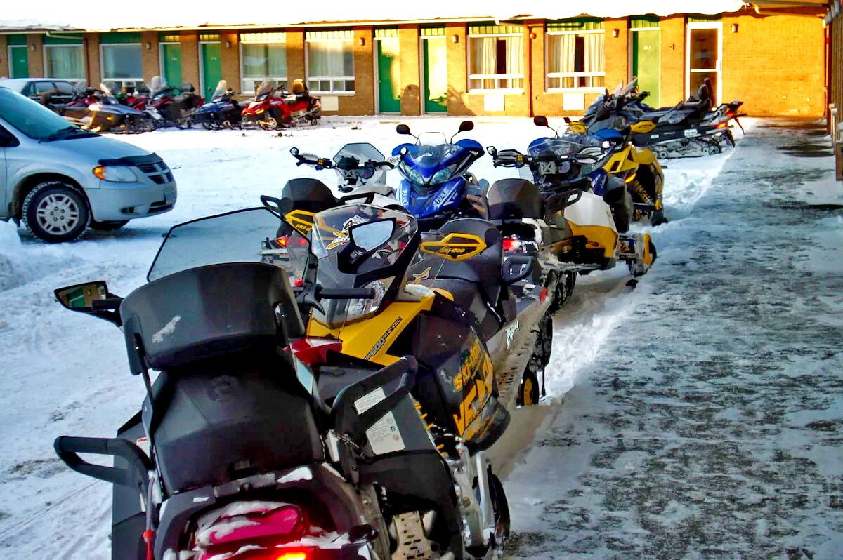 Une rangée de motos est stationnée dans un espace abrité, avec un bâtiment en arrière-plan.