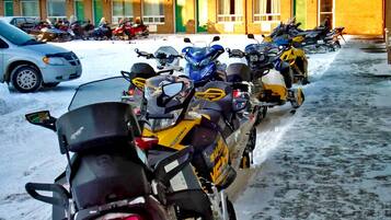 Une rangée de motos est stationnée dans un espace abrité, avec un bâtiment en arrière-plan.