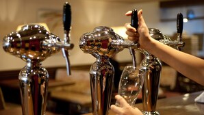 Un bar doté de trois tireuses métalliques, dont l’une est utilisée pour servir une boisson.