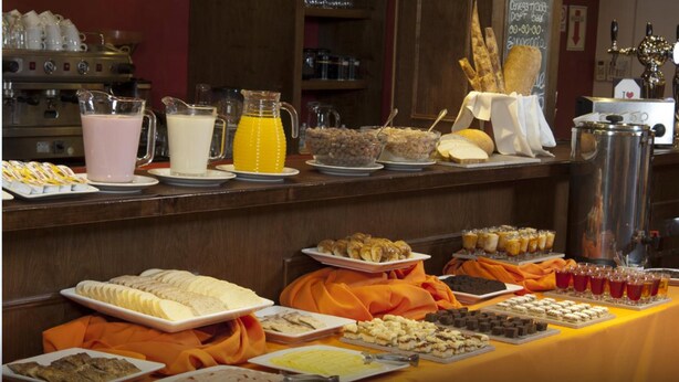 Un buffet proposant une variété de plats et de boissons, notamment des fruits, des pâtisseries et une machine à café.