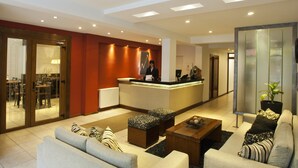 Un hall d’hôtel comprenant un comptoir d’accueil, un espace salon et une vue sur la salle à manger.