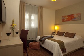 Een hotelkamer met een bed, nachtkastje, lamp en een schilderij aan de muur.