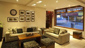 Un salon moderne comprenant un ensemble de canapés, une table basse et une grande fenêtre donnant sur une rue et des boutiques.
