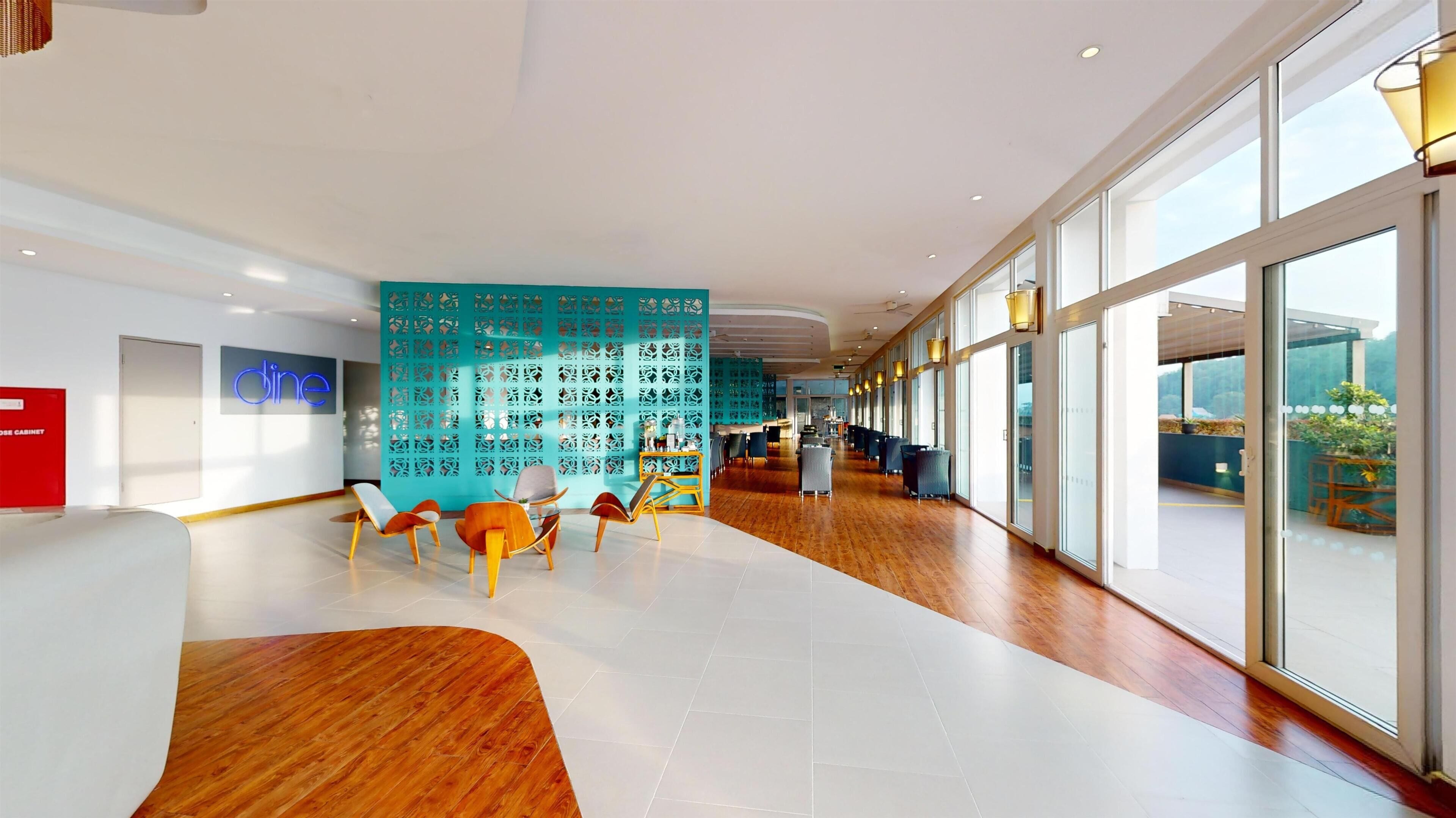 A modern hotel lobby with a wooden floor, a teal decorative wall, and a reception desk.