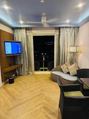 A modern living room with a flat-screen TV, a ceiling fan, a sofa, and a dining table.