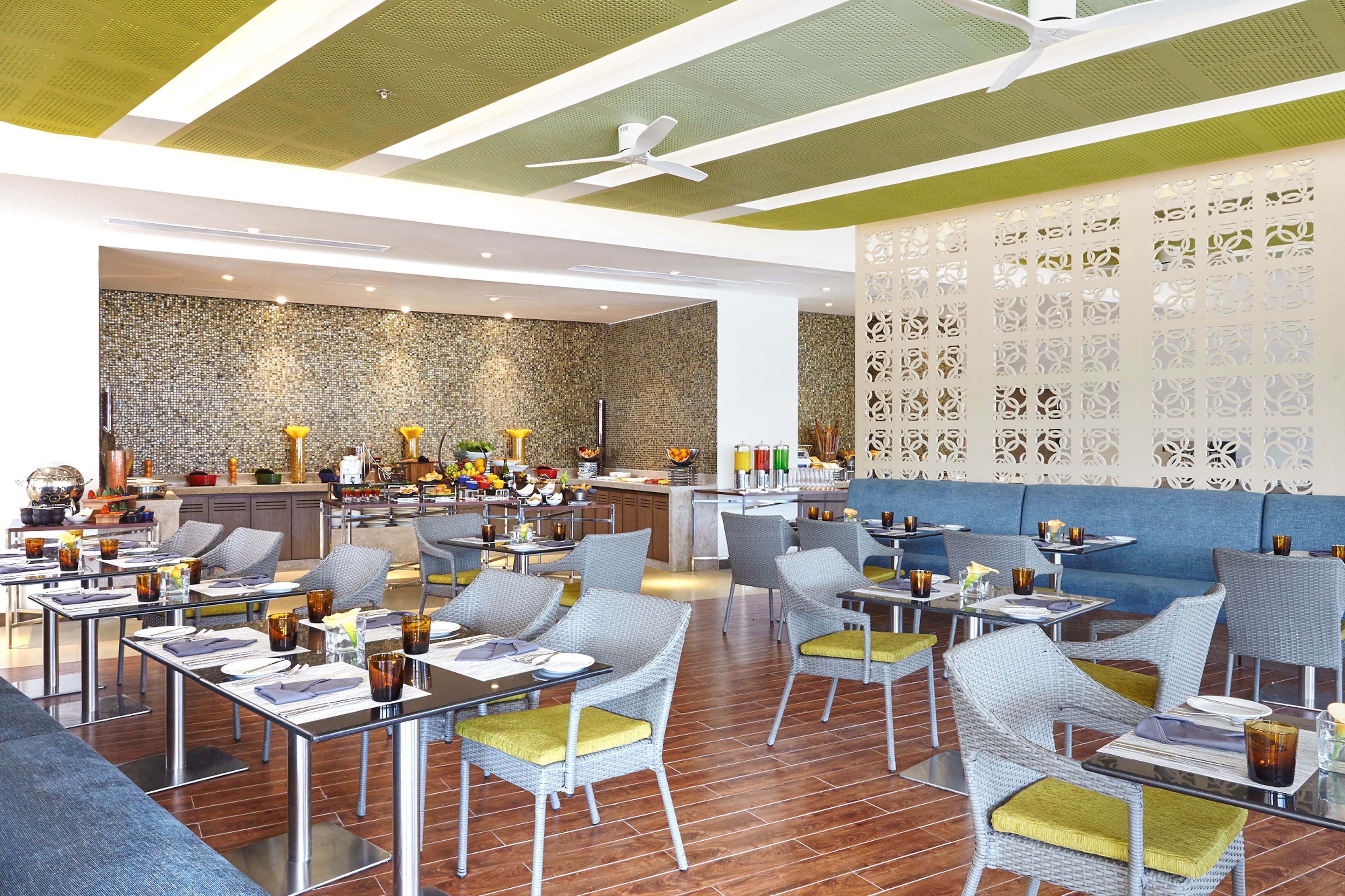Um restaurante moderno com cadeiras de vime, área de bar e uma parede decorativa.