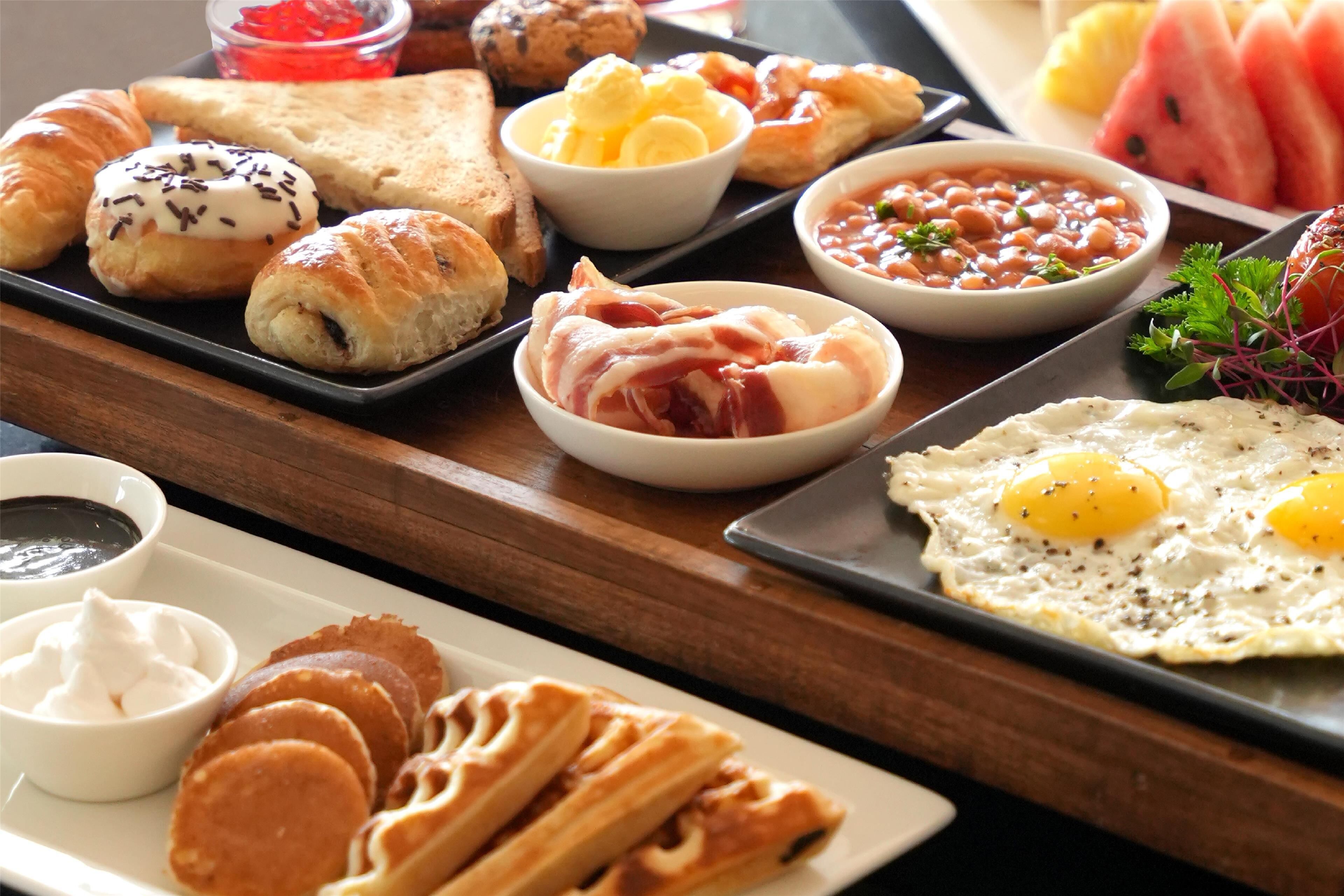 A breakfast buffet with various pastries, fruits, and dishes.