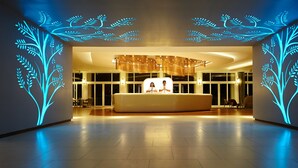 Una moderna zona de recepción con un mostrador central, ventanas amplias y luminarias decorativas en el techo.