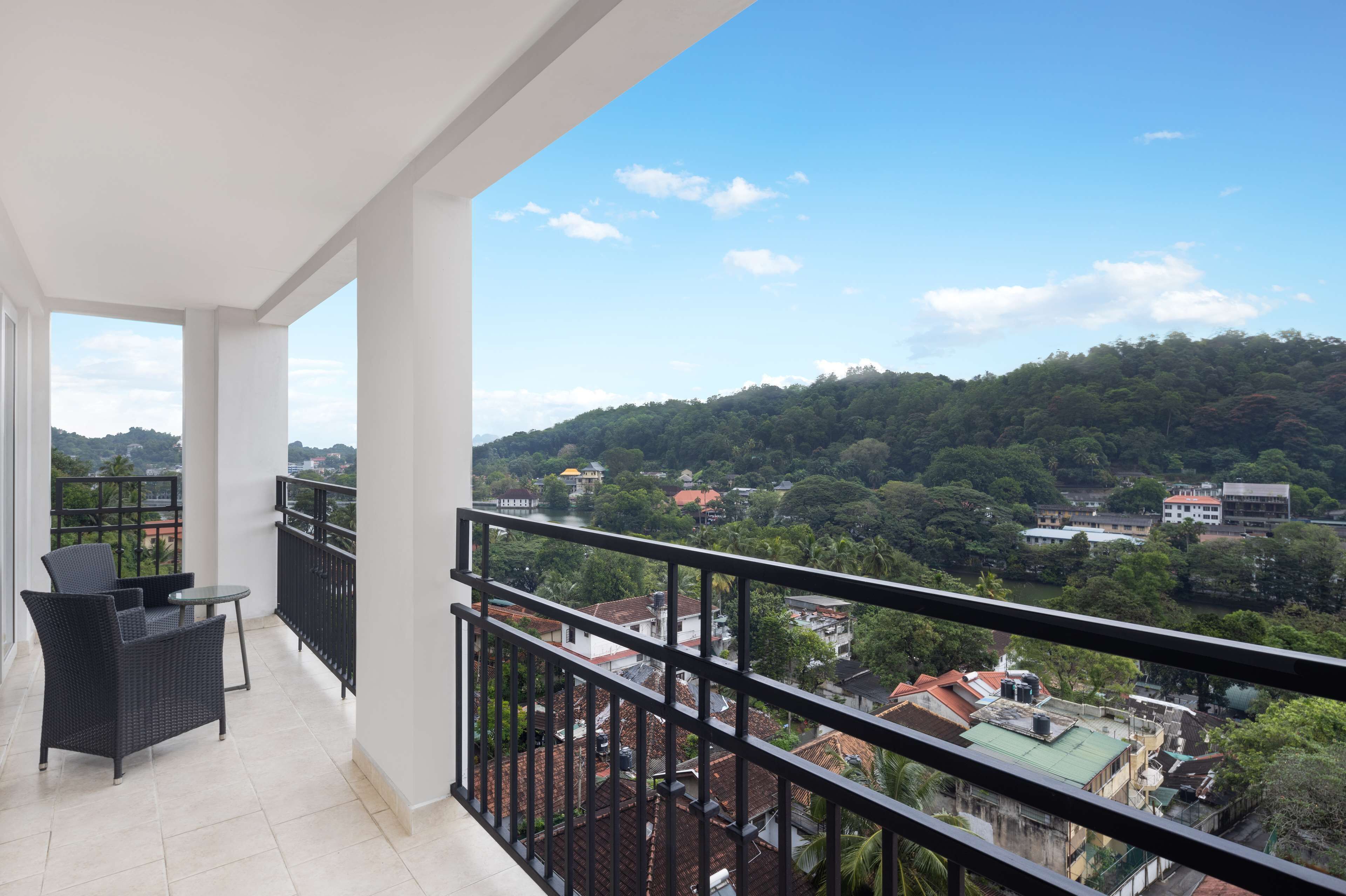 A balcony with a view of a hilly landscape and buildings.