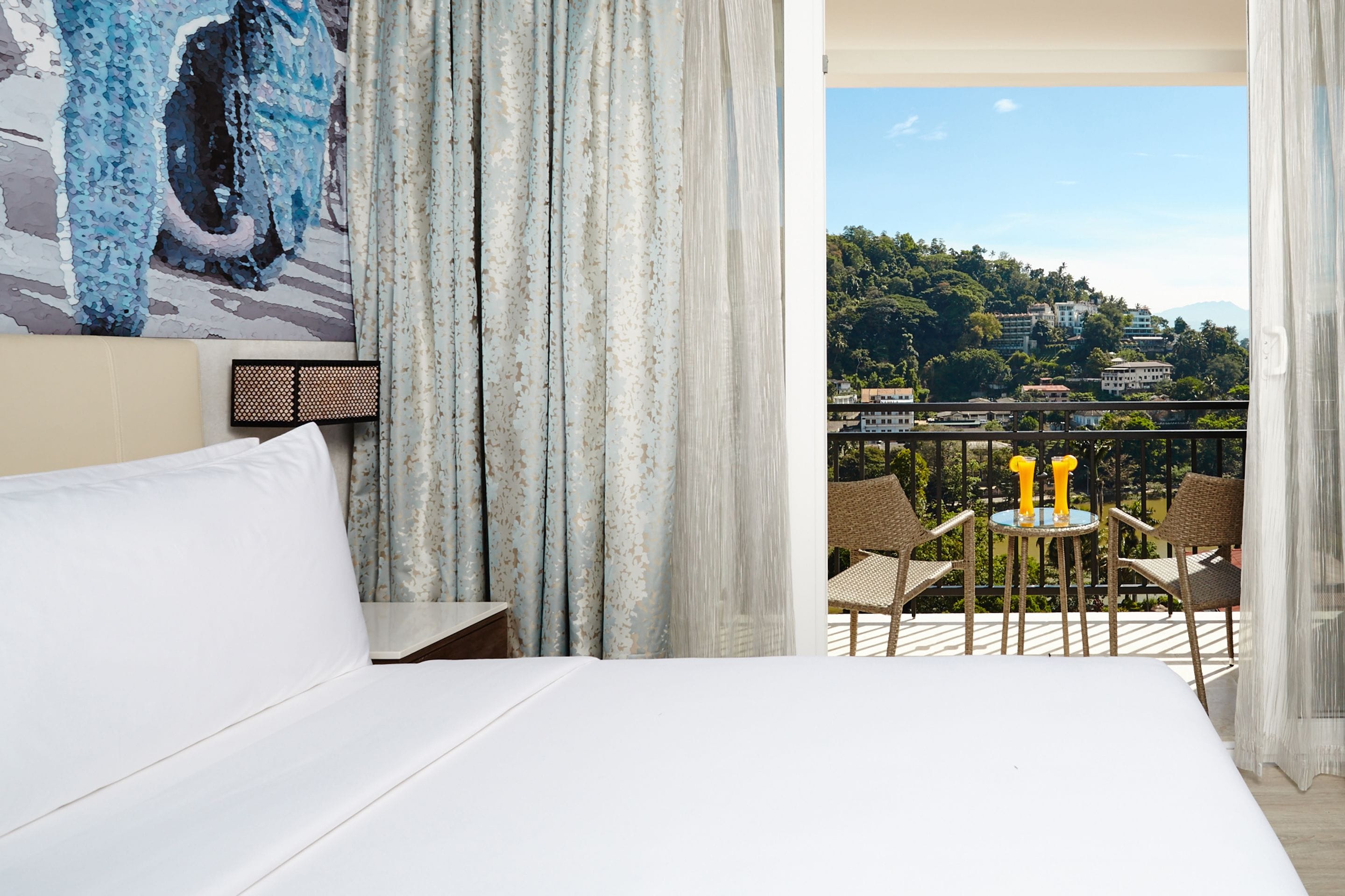 A hotel room with a balcony, a bed, and a view of a cityscape.