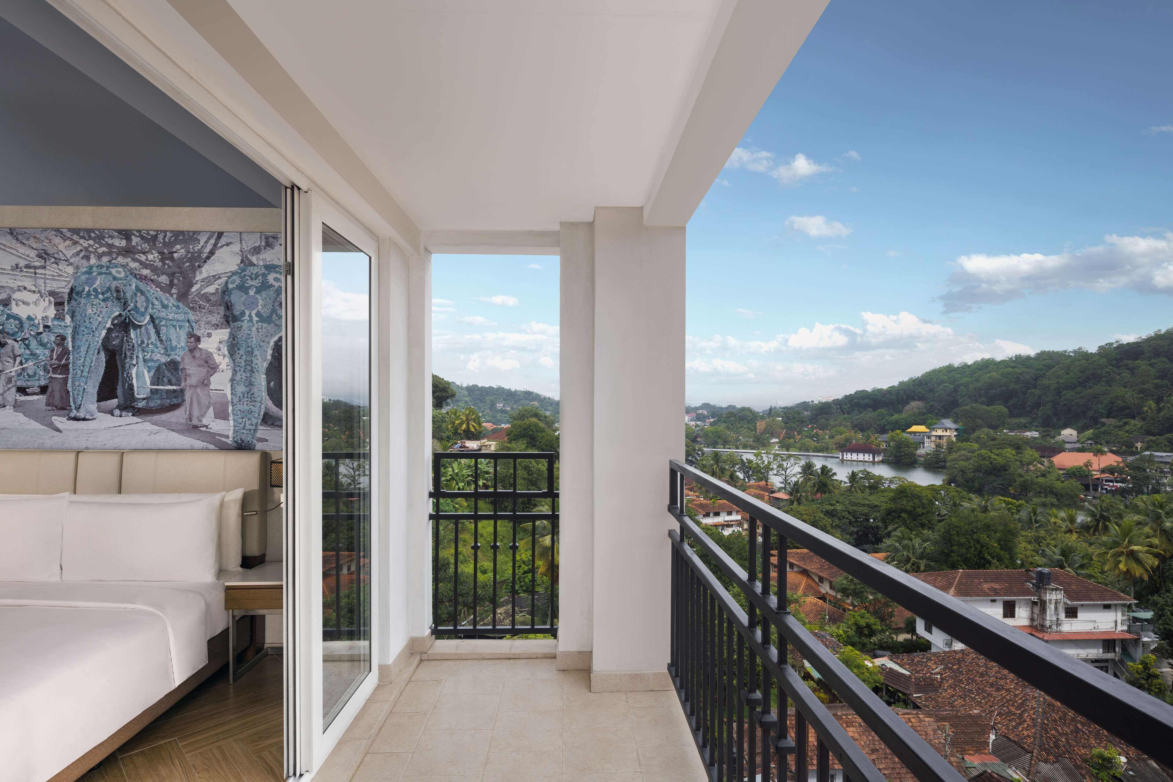 Un balcon avec un lit et une vue sur une rivière et la verdure.