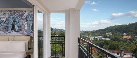 A balcony with a bed and a view of a river and greenery.