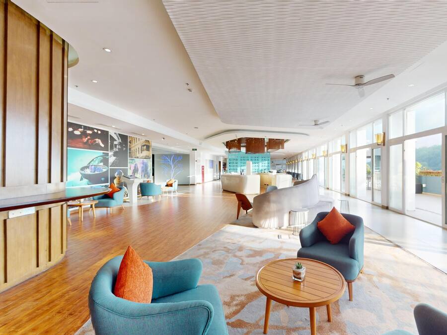 A spacious lobby with modern seating, a bar area, and large windows offering views.