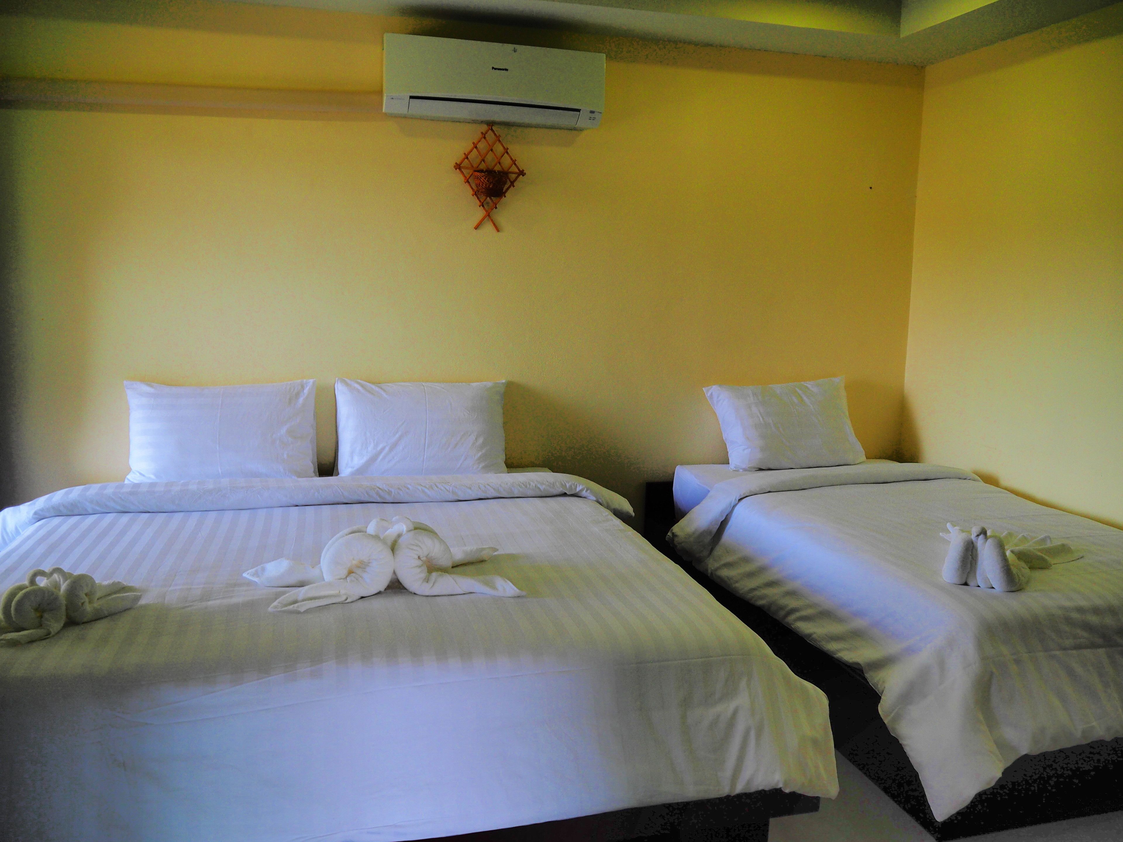 A hotel room with two beds, each with white linens and pillows, and a decorative swan on the beds.