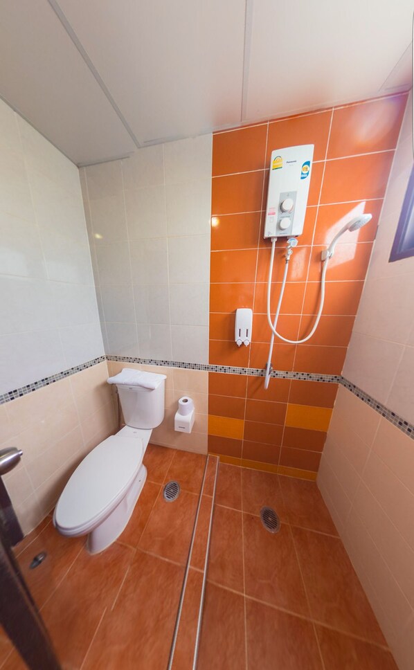 Un baño pequeño con inodoro, ducha y lavamanos.