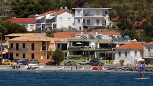 A coastal town with buildings, a beach, and parked cars.