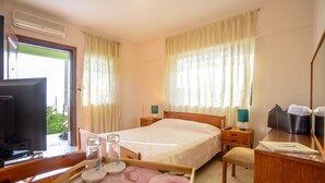A hotel room with a bed, a desk, a chair, a television, and a window with curtains.