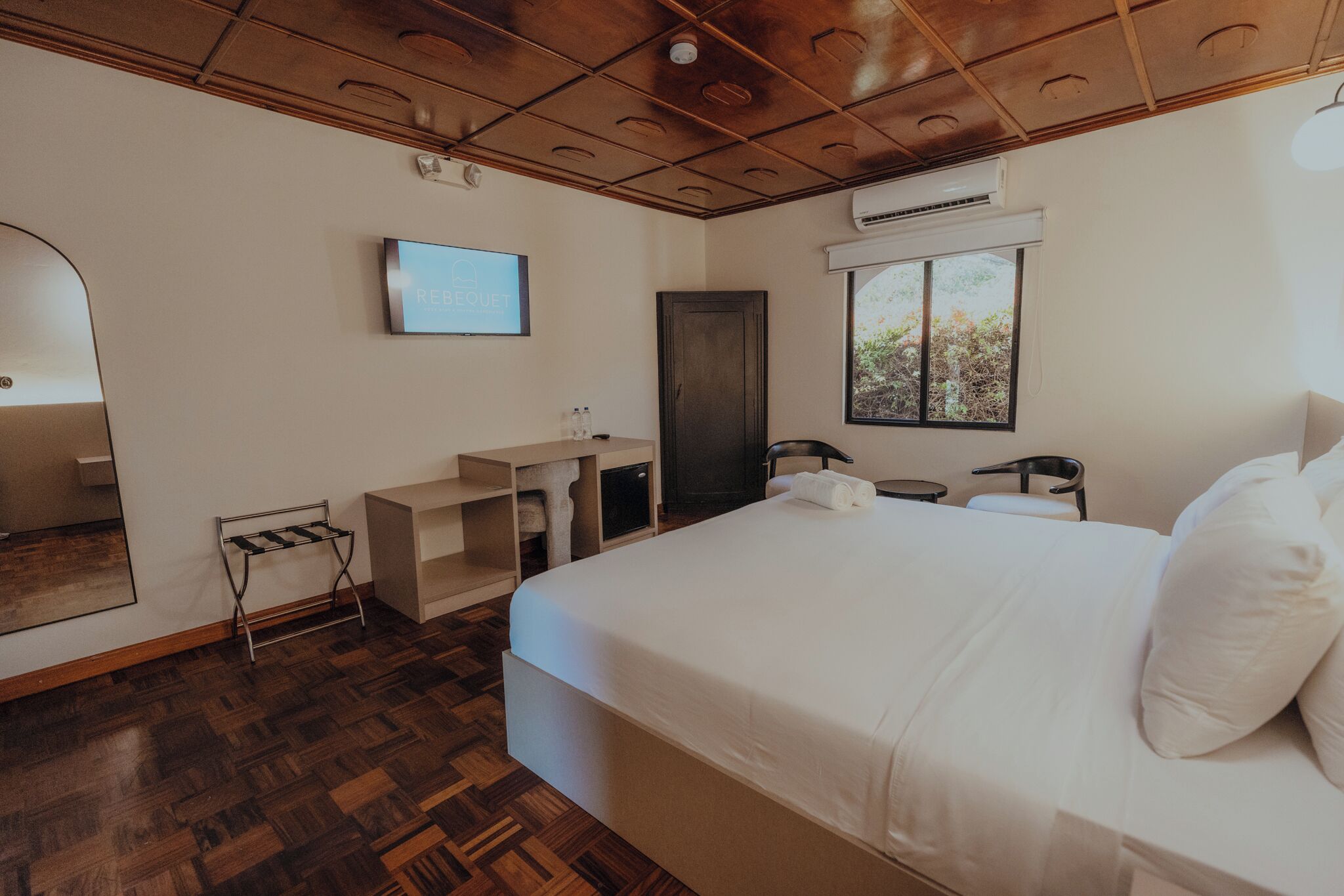 Ein Hotelzimmer mit einem großen Bett, einem Schreibtisch, einem Sessel, einem Fernseher und einem Fenster.