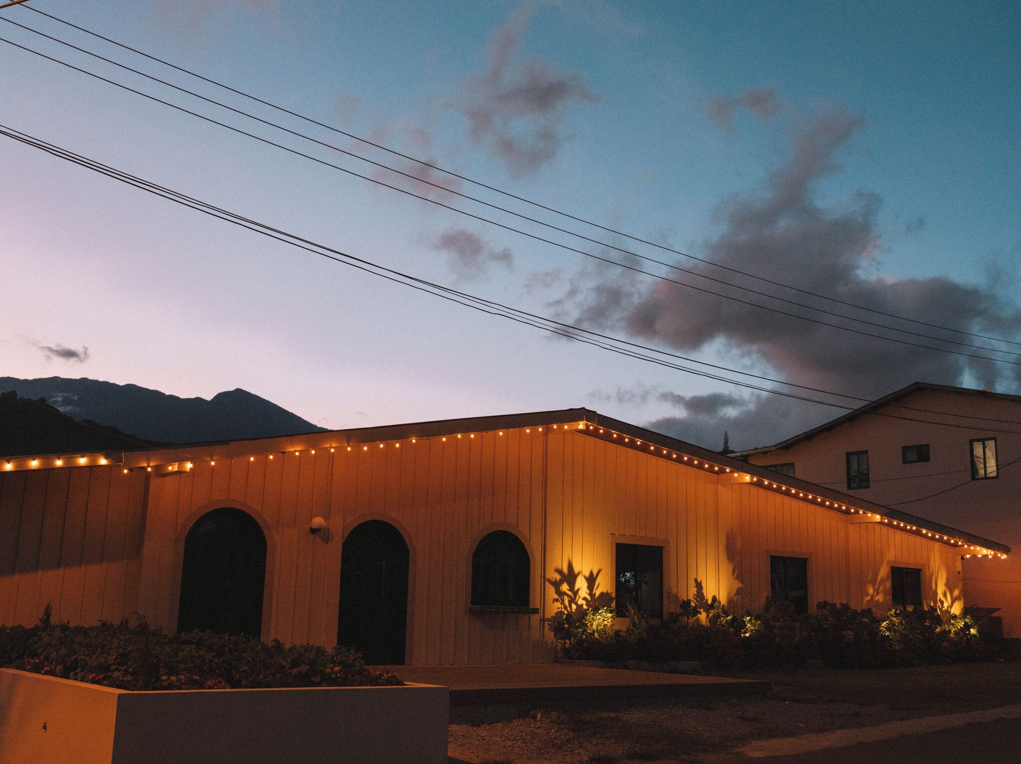 A building with a wooden facade, arched windows, and string lights.