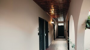 Un pasillo con suelo de baldosas, puertas negras y techo con diseños circulares.