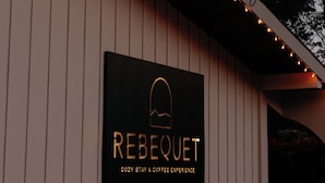 Un edificio con un cartel que dice "REBEQUET" y "EXPERIENCIA ACÓGEDA Y CAFÉ".