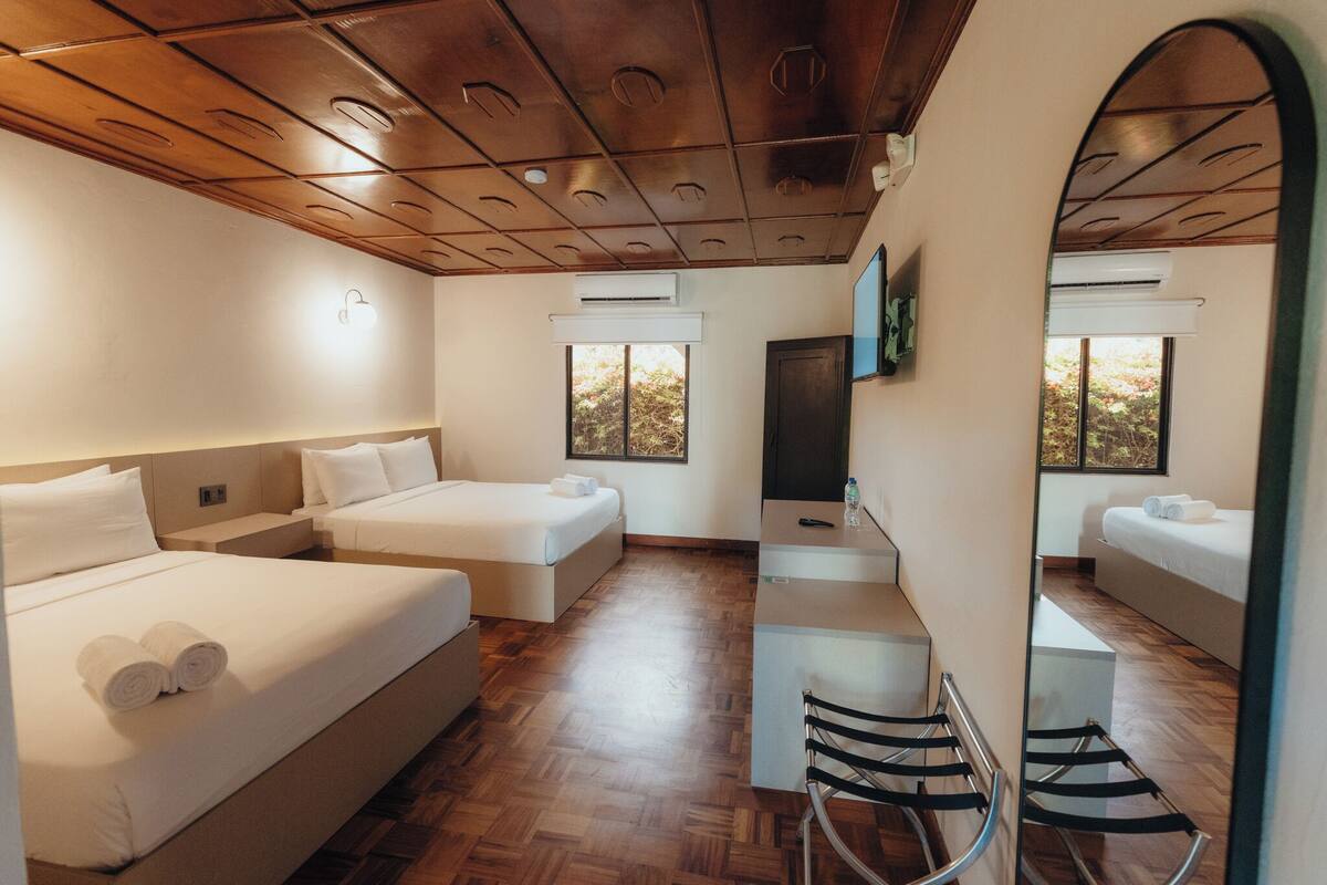 Una habitación de hotel con dos camas, un escritorio y una televisión.