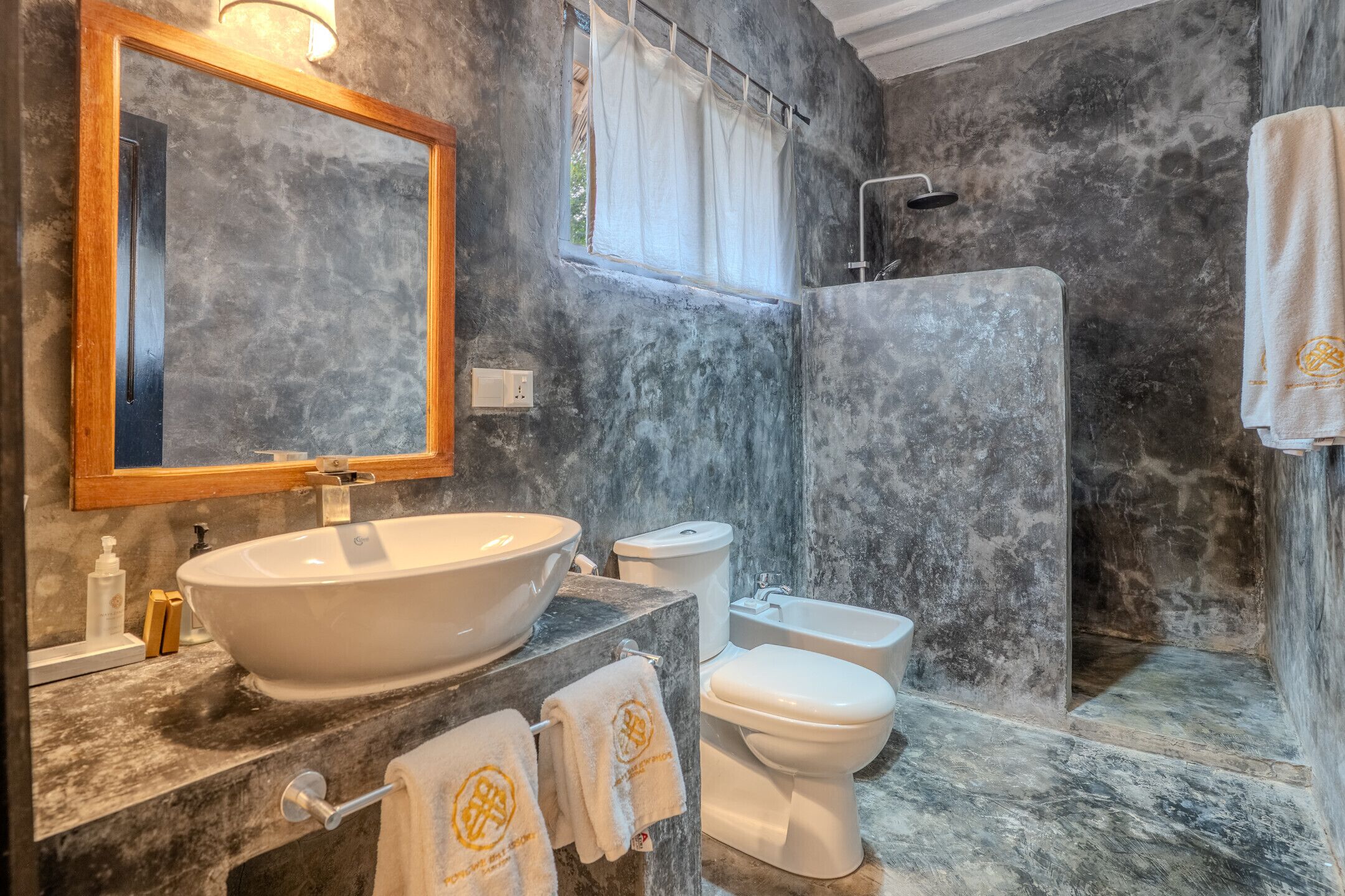A bathroom with a large oval sink, a toilet, and a shower area.