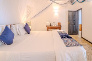 Una habitación de hotel con cama, escritorio, silla, mesita de noche y puerta.