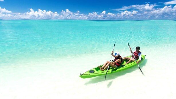 A kayak on a clear turquoise sea with a white sandy beach and a blue sky with clouds. - Pongwe Bay Resort (Pongwe)