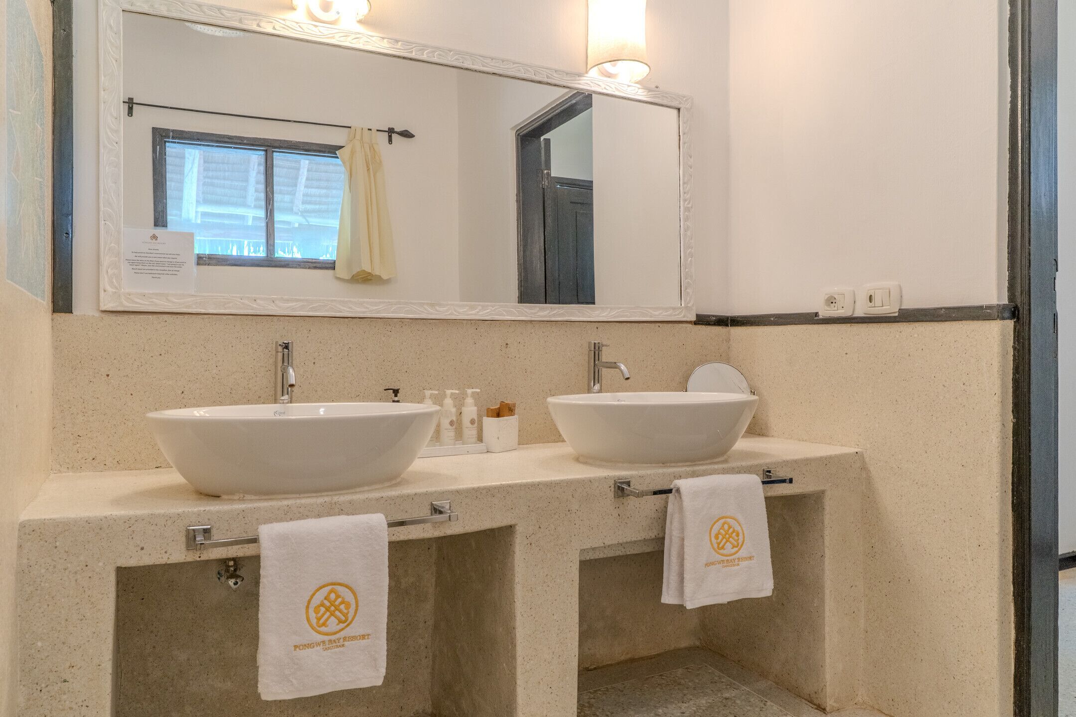 Une salle de bain avec deux lavabos, un miroir et des serviettes accrochées au mur.
