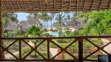 A resort with thatched-roof buildings, a swimming pool, and lush tropical vegetation.