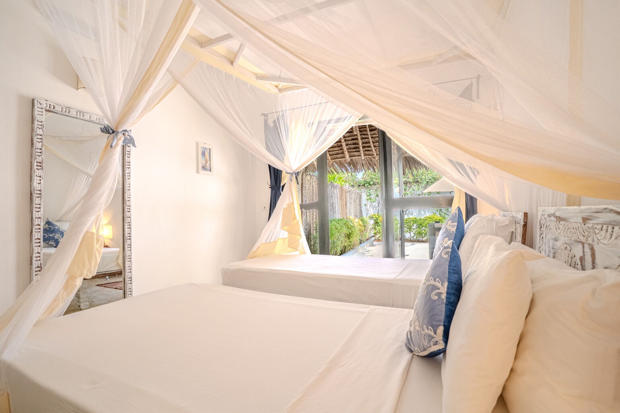 Un dormitorio con cama con dosel, un espejo grande y vistas a la vegetación.