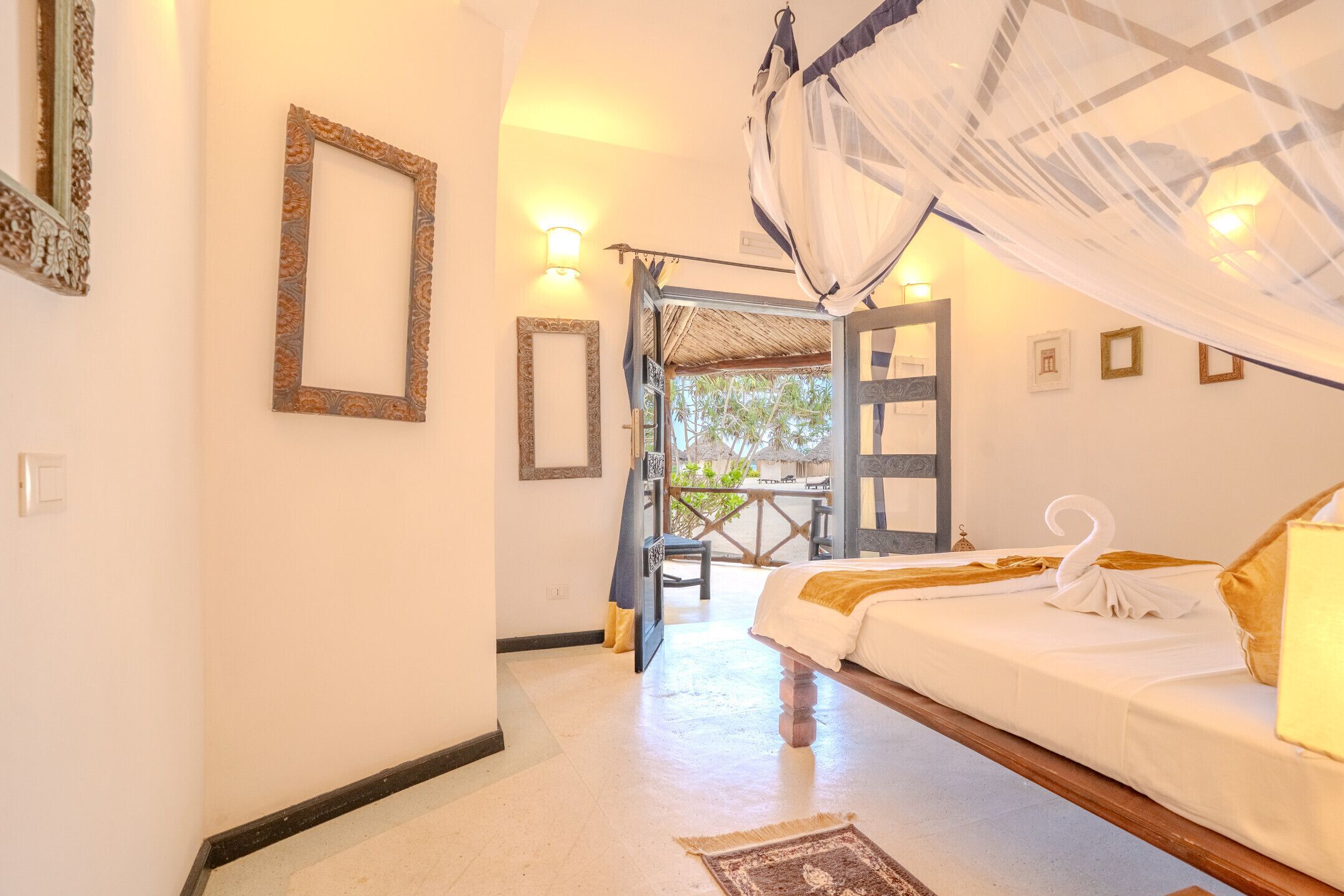 Une chambre d’hôtel avec un lit, une porte donnant sur un espace extérieur et des lampes fixées au mur.