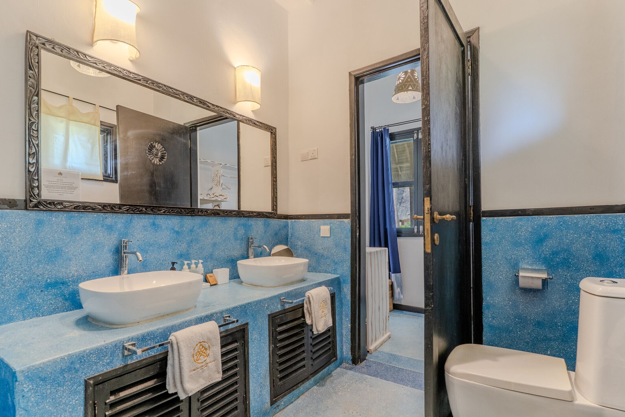 A bathroom with two sinks, a toilet, and a mirror.