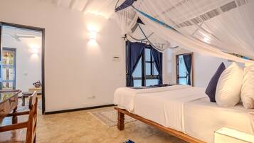 A bedroom with a bed, a chair, a desk, and a window with curtains.