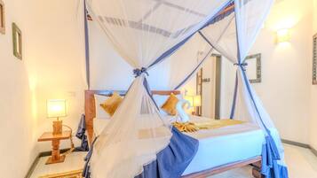 A bedroom with a four-poster bed, a nightstand, a lamp, and a mirror.