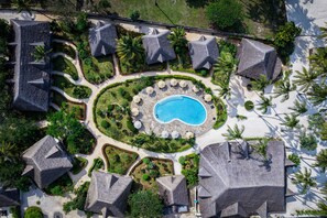 A resort with a central swimming pool, surrounded by landscaped gardens and multiple bungalow-style buildings. - Pongwe Bay Resort (Pongwe)