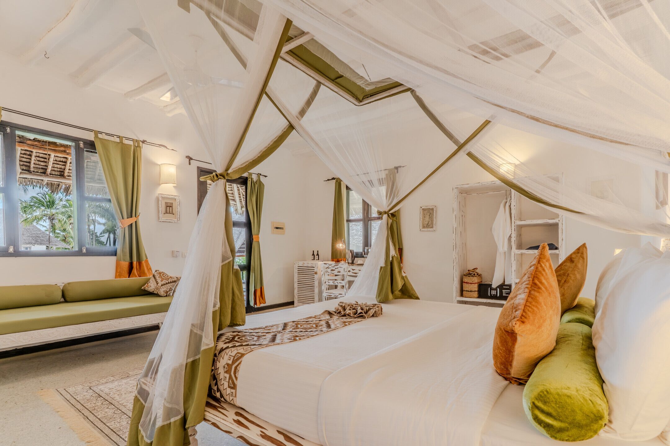 Una habitación con una cama, un sofá verde y una ventana con cortinas.