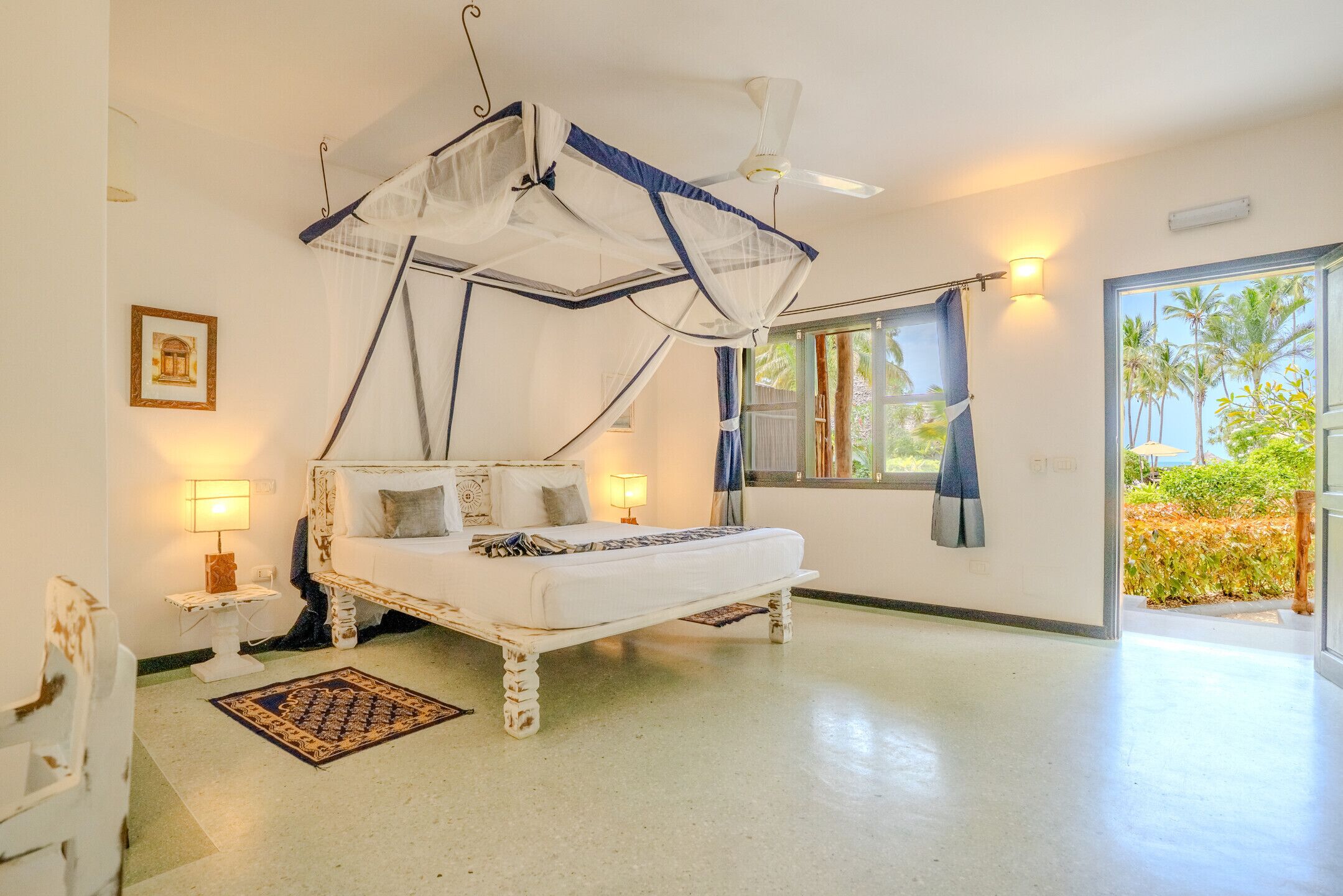 Un dormitorio con cama, lámparas de noche, ventana con cortinas y vistas al exterior.