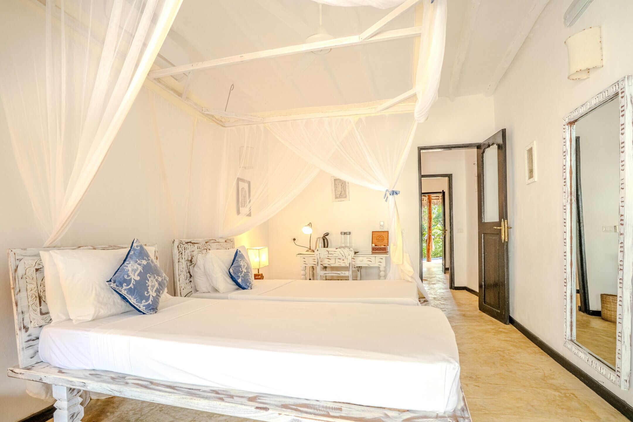 Un dormitorio con cama, mesita de noche, lámpara y espejo.