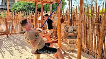 Relax in a serene outdoor setting with a rope swing and a hanging basket amidst palm trees.