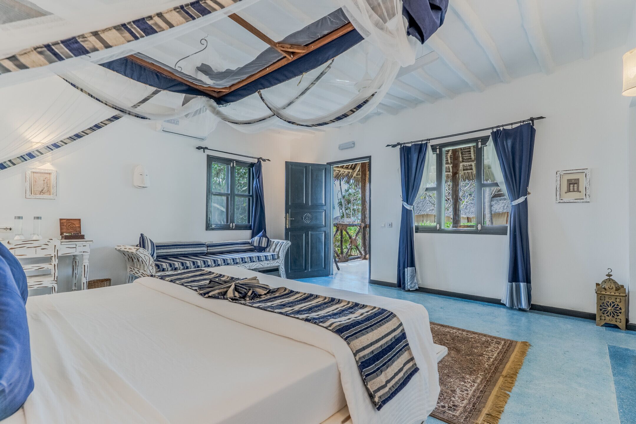 A bedroom with a large bed, a desk, and a view of the outside.