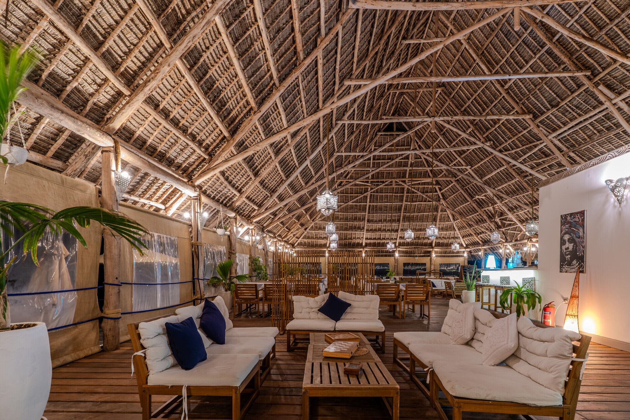 An indoor venue with a high ceiling, wooden furniture, and decorative lighting.