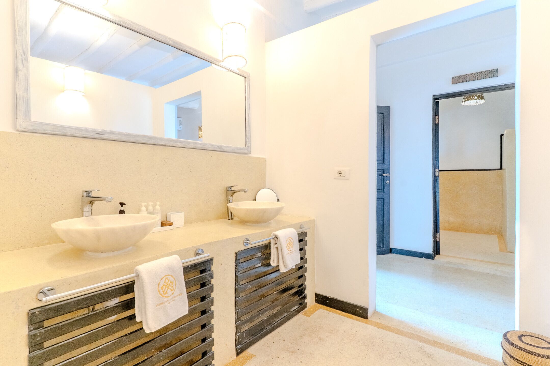 Une salle de bain avec un double lavabo, un grand miroir et un porte-serviettes.