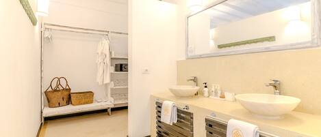 A bathroom with a bathtub, two sinks, a mirror, and a towel rack.